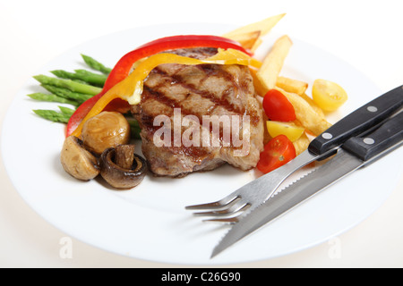 Steak de surlonge de veau, servi avec des asperges, tomates cerises, champignons grillés, des rubans rouges et jaunes de capsicum et de frites. Banque D'Images