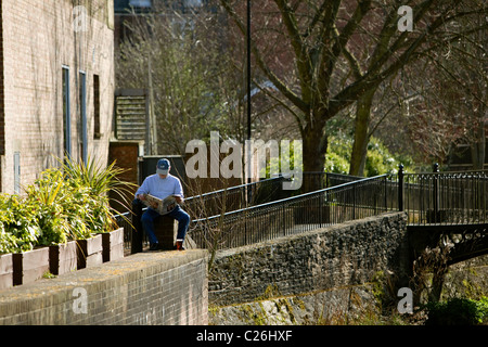 L'homme ayant un quartier calme de lire en dehors des journaux avec pint glass.Salisbury Angleterre Banque D'Images