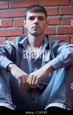 Portrait of young handsome guy brunet posant près de red brick wall Banque D'Images