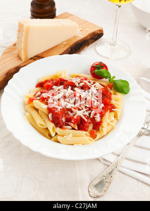 Une assiette de pâtes penne avec sauce tomate et fromage parmesan râpé Banque D'Images