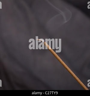 Joss stick d'encens brûlant de traînée de fumée sur un fond sombre. Banque D'Images