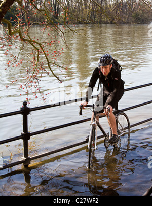 Un cycliste à faire face à la Tamise de halage inondés à marée haute du Strand-sur-le-Vert, Chiswick Banque D'Images