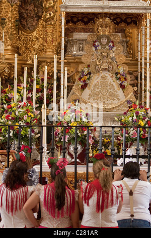 Pèlerins catholique agenouillé devant la Vierge d'El Rocio à l'intérieur du sanctuaire à El Rocio, au cours de la Romeria. Banque D'Images