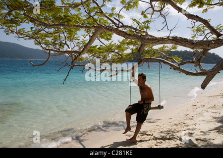 Homme assis sur une plage swing, Parc national marin de Tarutao, Thaïlande Banque D'Images