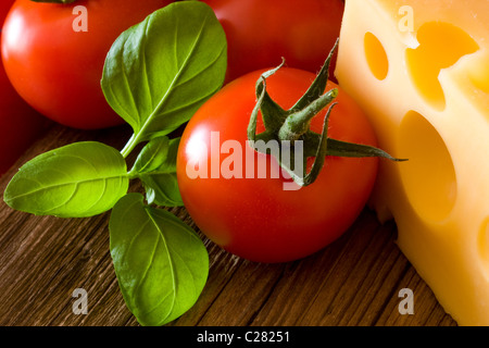 Les tomates, le basilic et le fromage sur la vieille planche de bois Banque D'Images