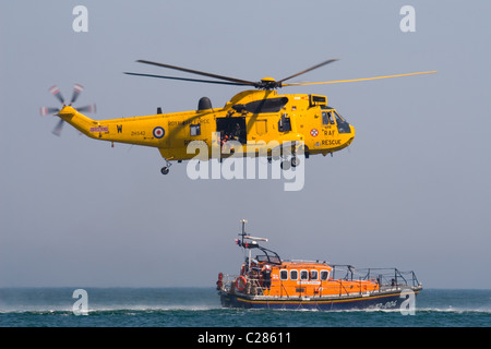Un RAF Westland Sea King HAR3/3A suspendu au-dessus d'un bateau de sauvetage de la RNLI en mer du Nord,UK Banque D'Images