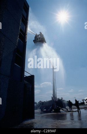 Fireman pulvériser de l'eau d'un tuyau flexible monté sur une échelle de la benne d'un camion d'incendie Banque D'Images