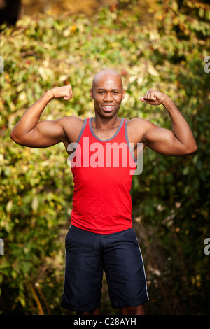 Un homme de la torsion ses biceps - isolé contre un livre vert Banque D'Images