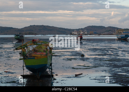 Les bateaux de pêche locaux en bois rester coincé sur un sol en eau peu profonde près de la rive dans un faible temps d'eau Banque D'Images