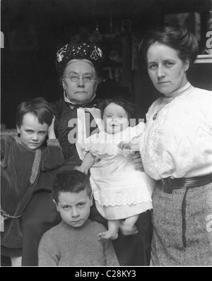 Portrait négatif en verre de l'ère édouardienne original d'une famille édouardienne respectable. La femme aînée est une matriarche très sévère encore vêtue de vêtements de style victorien avec sa fille ou sa belle-fille et sa famille à l'entrée de leur maison, au Royaume-Uni vers 1912 Banque D'Images