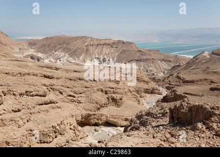 Désert rocheux d'Israël, près de la voie sèche. La mer morte est dans la distance. Banque D'Images