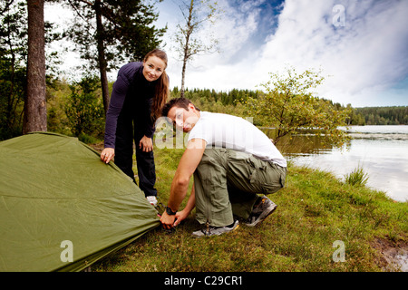 Un homme et une femme camping - mise en place d'une tente Banque D'Images