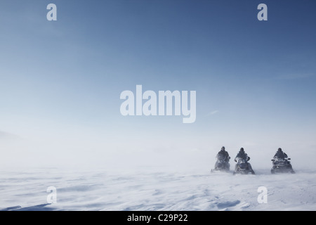 Trois motoneiges sur un paysage d'hiver stérile de soufflage Banque D'Images