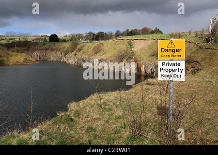 L'eau profonde d'un panneau d'avertissement à une carrière inondée juste à l'extérieur de Stanhope dans Weardale, Angleterre du Nord-Est, Royaume-Uni Banque D'Images