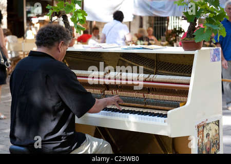 Le pianiste joue pour les consommateurs et aux touristes de passage dans le centre d'Uzès, Gard, Languedoc-Roussillon, France. Banque D'Images