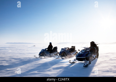 Un paysage d'hiver avec poudrerie et trois motoneiges. Banque D'Images