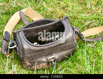 Une cartouche en cuir sac avec 12 cartouches dans l'alésage à l'herbe Banque D'Images