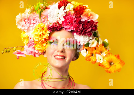 La fille de fleur. Belle jeune fille portant des couronnes de fleurs. Maquillage créatif avec de longs cils artificiels en plumes Banque D'Images