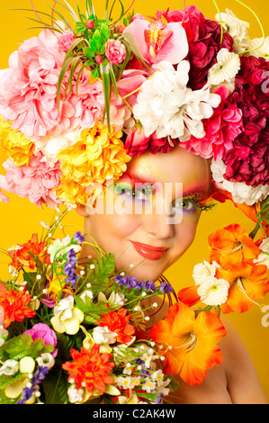 La fille de fleur. Belle jeune fille portant des couronnes de fleurs. Maquillage créatif avec de longs cils artificiels en plumes Banque D'Images