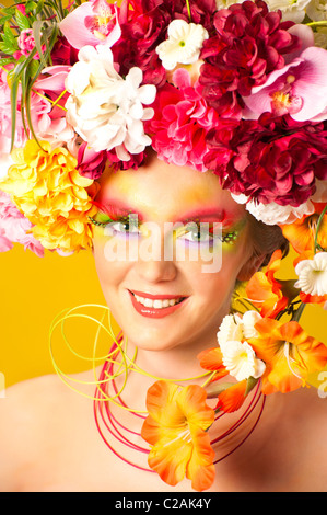 La fille de fleur. Belle jeune fille portant des couronnes de fleurs. Maquillage créatif avec de longs cils artificiels en plumes Banque D'Images