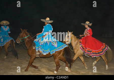 Spectacle mexicain actrices sur les chevaux équitation sur la plage horaire du soir sombre océan Banque D'Images