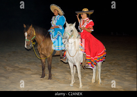 Spectacle mexicain actrices sur les chevaux équitation sur la plage de sable de l'océan temps sombre soir Banque D'Images