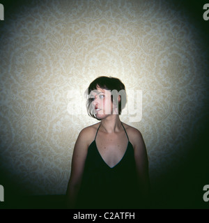 Young woman leaning against wall, looking away, portrait Banque D'Images