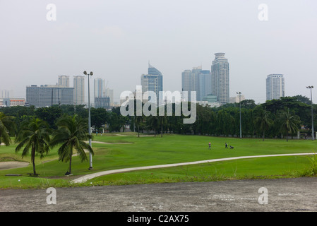 Philippines, Manille, Luzon, terrain de golf avec des toits de la ville en arrière-plan Banque D'Images