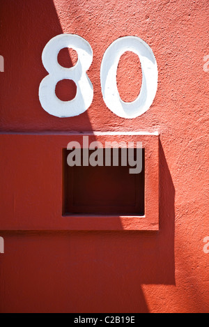 Numéro de la maison et une boîte aux lettres sur le mur rouge Banque D'Images