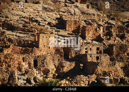 Oman, Ghul, ensoleillée traditionnelles maisons et plantations de palmiers dans le village d'une montagne rocheuse à l'arrière-plan Banque D'Images