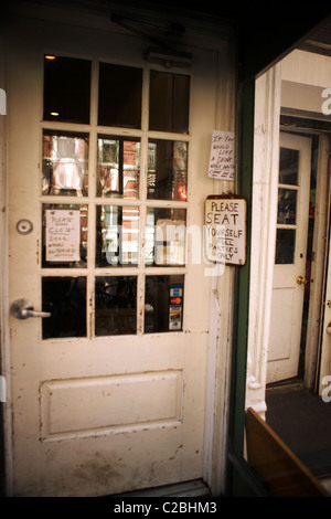 Entrée d'un restaurant dans le West Village, New York avec divers signes bizarres collé à la porte. Banque D'Images