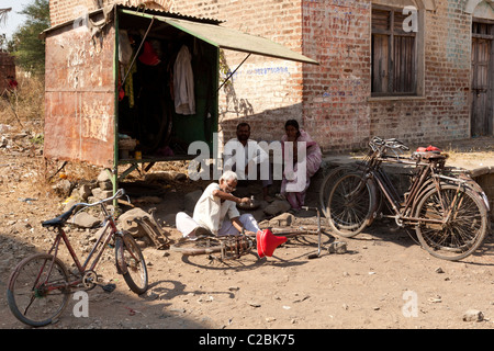 Un vieil homme de réparation de vélos indiens travaillant par son échoppe dans Valsang Village Maharashtra Inde Banque D'Images