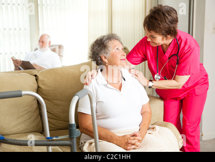 Senior woman dans une maison de soins infirmiers, avec une infirmière de soins. Banque D'Images