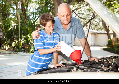 Le père et le fils de changer l'huile à moteur dans la voiture familiale. Banque D'Images