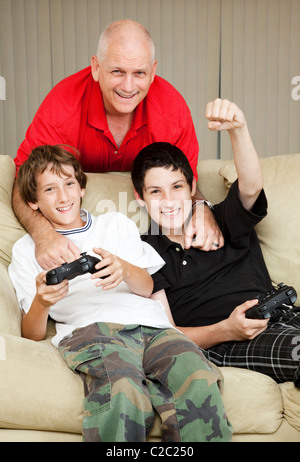 Père passe du temps avec ses fils, jouer à des jeux vidéo. Banque D'Images
