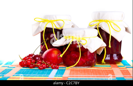 Pots de confiture de framboises, confiture de prunes confiture de pommes et sur table, isolé sur blanc. Banque D'Images
