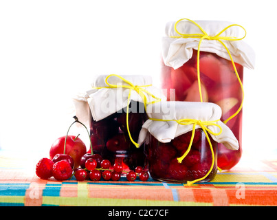 Pots de confiture de framboises, confiture de prunes confiture de pommes et sur table, isolé sur blanc. Banque D'Images