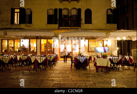 Un serveur dans un restaurant vide la nuit, Venise Italie Banque D'Images