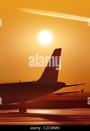 Grand avion de passagers est en attente de départ dans l'aéroport, coucher du soleil Banque D'Images