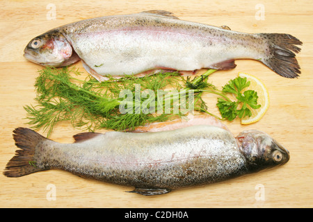 Deux truites arc-en-ciel fraîche sur une carte avec des herbes et du citron Banque D'Images