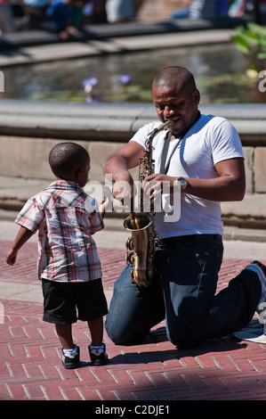 Un jeune garçon fait don d'argent à un saxophoniste dans Central Park, New York City, USA. Banque D'Images