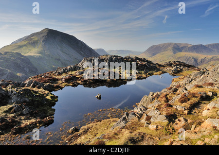 Tarn sur le sommet du foin dans le Lake District, avec une haute falaise et Grasmoor en arrière-plan Banque D'Images