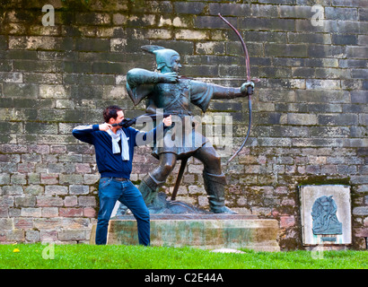 Tourist posant pour photographier à côté de la statue de Robin des Bois à l'extérieur le château de Nottingham England UK par James Woodford [1893-1976] Banque D'Images