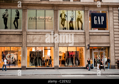 Magasin GAP à Manhattan, New York City, États-Unis, avec de grandes vitrines avec des publicités de mode et des gens sur le trottoir. Banque D'Images