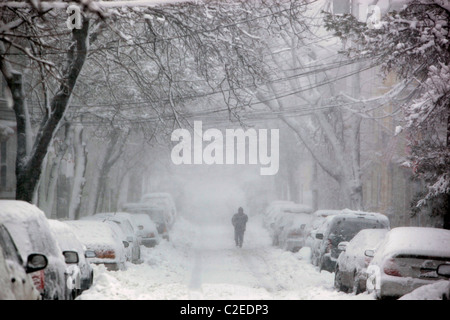 Une personne marche sur une rue couverte de neige pendant une tempête hivernale dans la région de Boston Massachusetts Banque D'Images