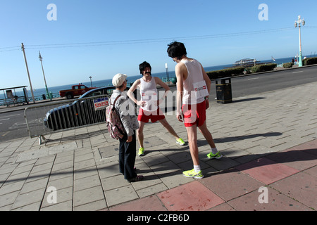 Une dame à discuter avec deux 118118 runner en dehors de la travestis Brighton Centre sur le front de mer de Brighton East Sussex, Royaume-Uni. Banque D'Images