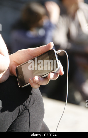 Détail de femme tenant l'iphone à Sun à l'extérieur Banque D'Images