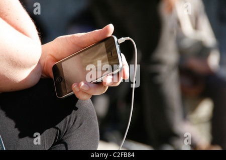 Détail de femme tenant l'iphone à Sun à l'extérieur Banque D'Images