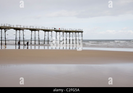 Pier pâle et sable avec 2 Dog Walkers Banque D'Images