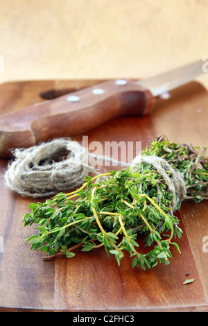 Bouquet de thym frais et un couteau sur une planche en bois Banque D'Images